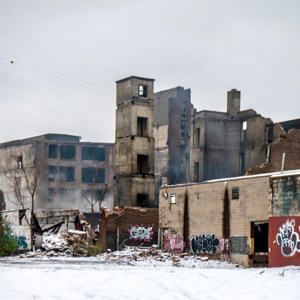 Ruins of the Crunden-Martin Manufacturing Company complex, featuring charred walls, graffiti, and remnants of the structure surrounded by snow.