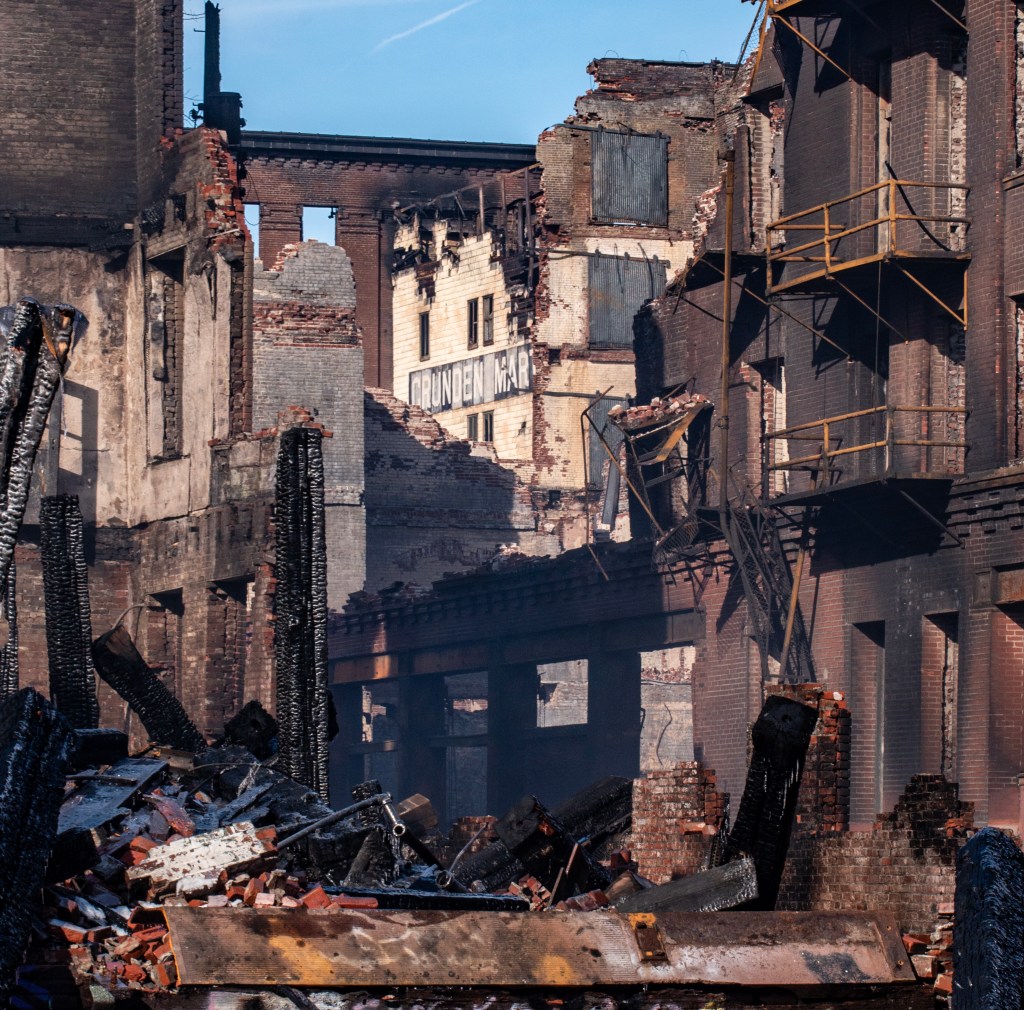 A view of the Crunden-Martin Manufacturing Company complex showing charred remnants and collapsed structures after a devastating fire, with the name 'Crunden Mart' visible amidst the ruins.