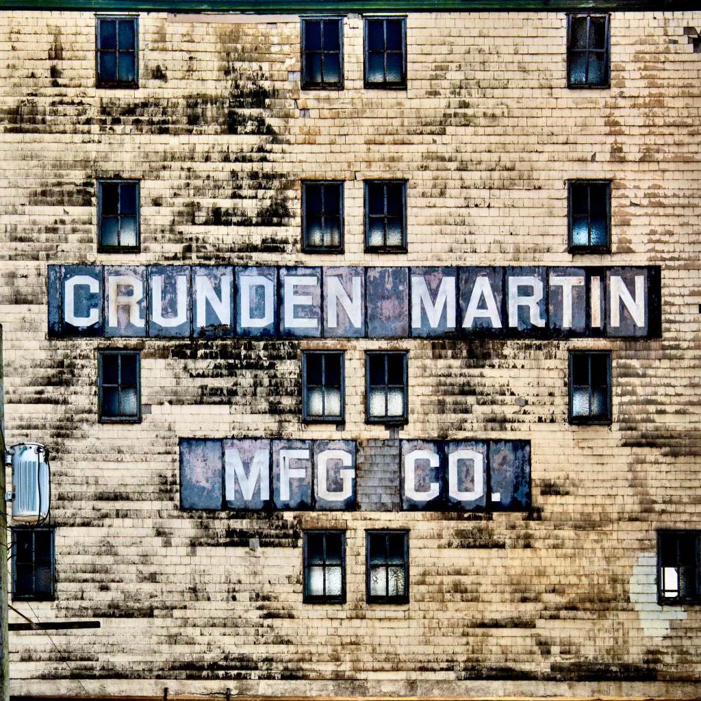 Close-up view of the Crunden-Martin Manufacturing Company sign on a weathered building facade, showcasing the historic name of the complex.