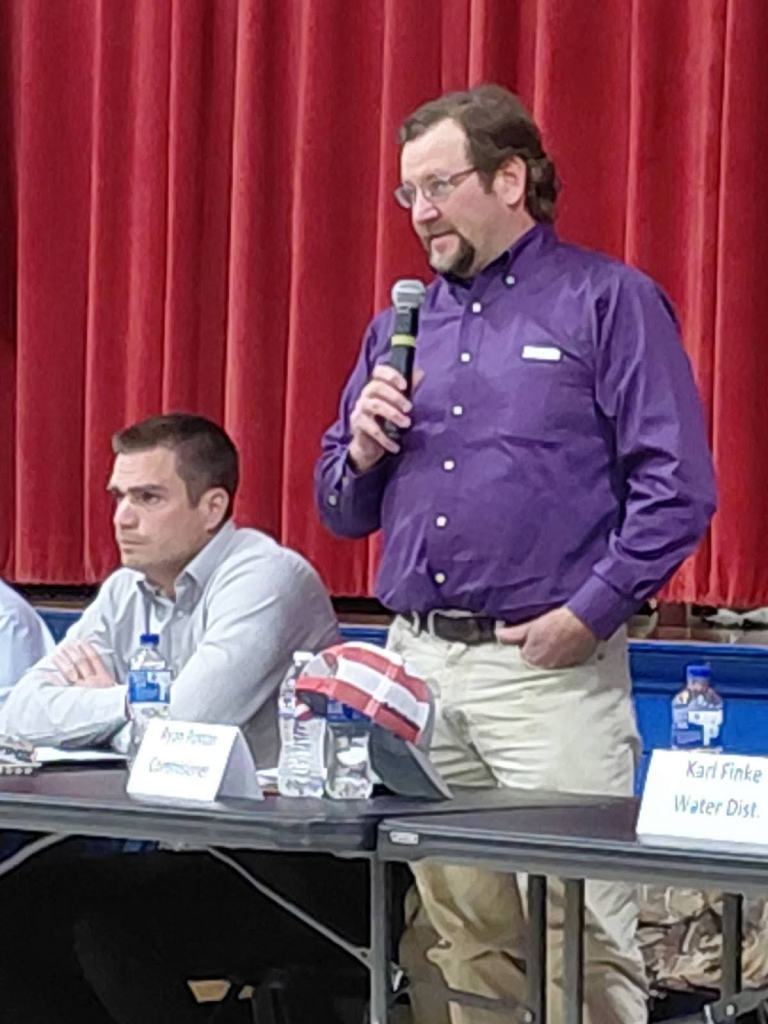 A panel of local government representatives, including a man speaking into a microphone, addresses attendees during an information session about proposed data centers in Montgomery City.