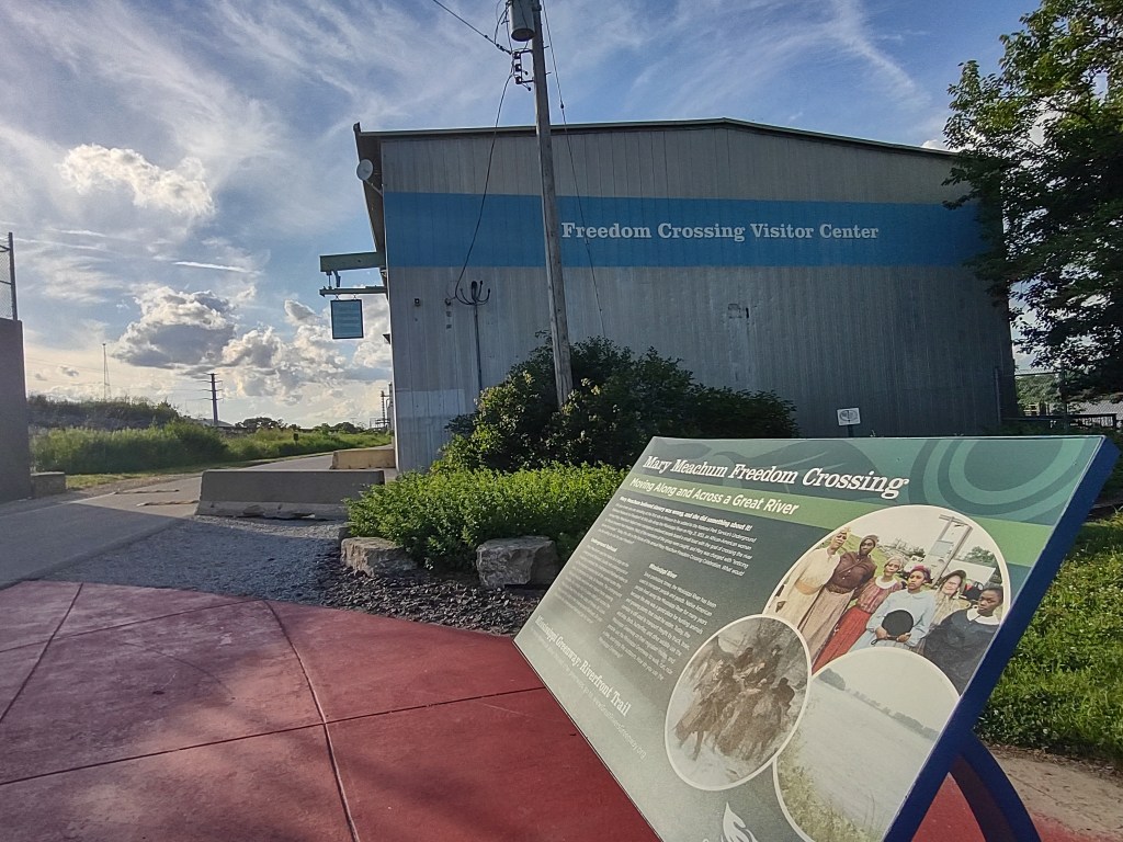 Exterior view of the Freedom Crossing Visitor Center with a historical sign about the Mary Meachum Freedom Crossing, featuring informational text and images related to the Underground Railroad.